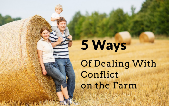 a happy family with young children on the farm leaning on a hay bale